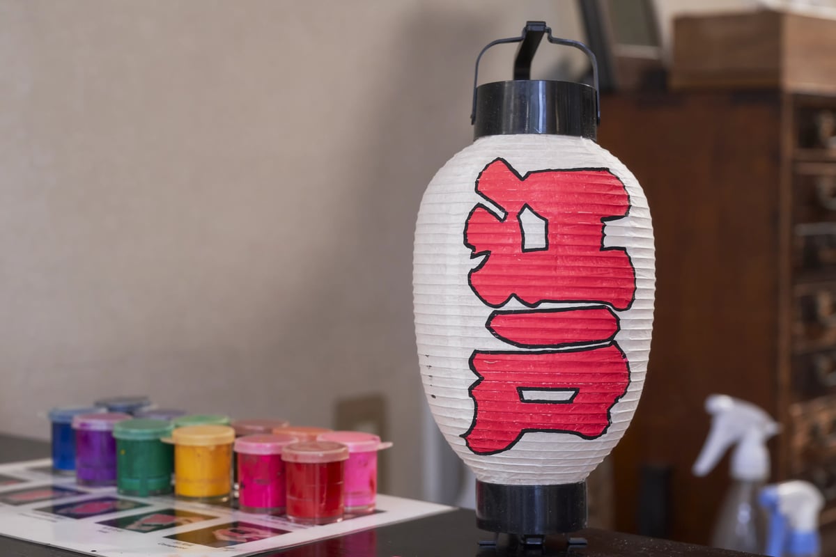 Pots of coloured paint beside a lantern lettered in red