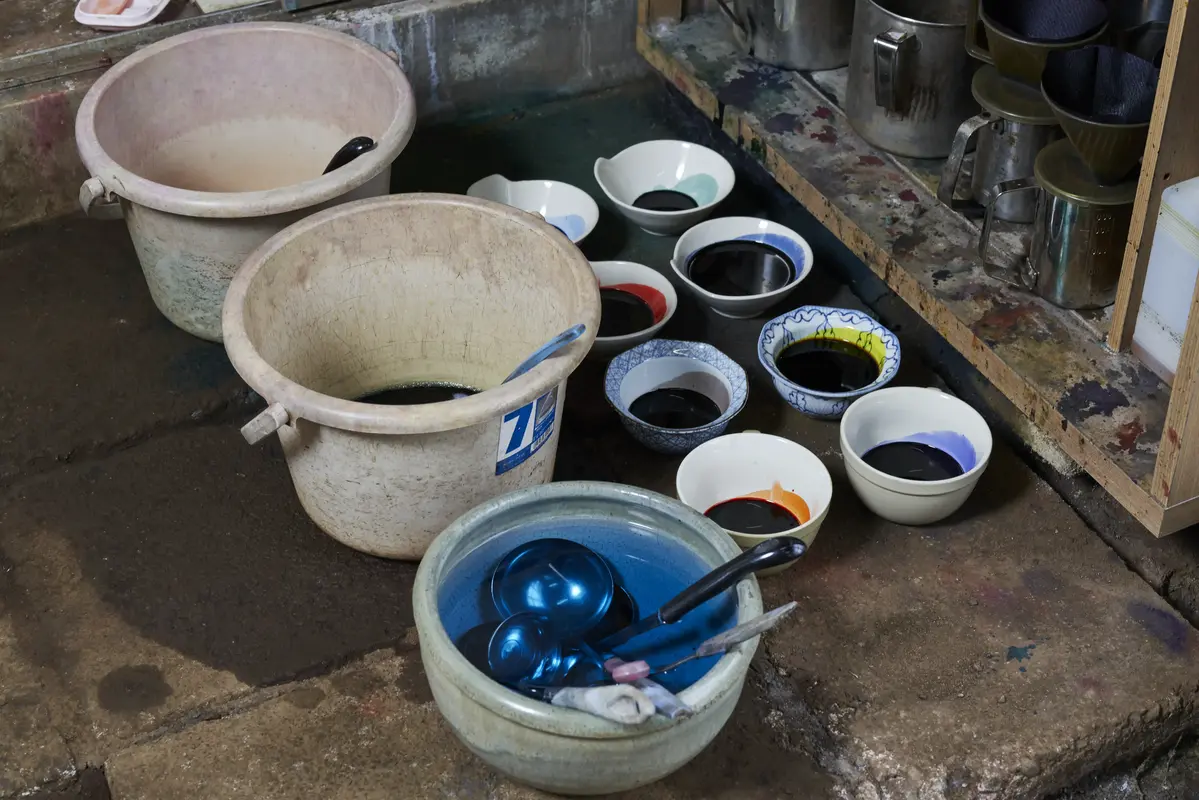 Bowls and buckets of mixed dye on the workshop floor