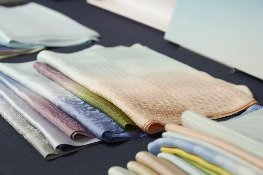 Folded lengths of dyed silk in soft colours