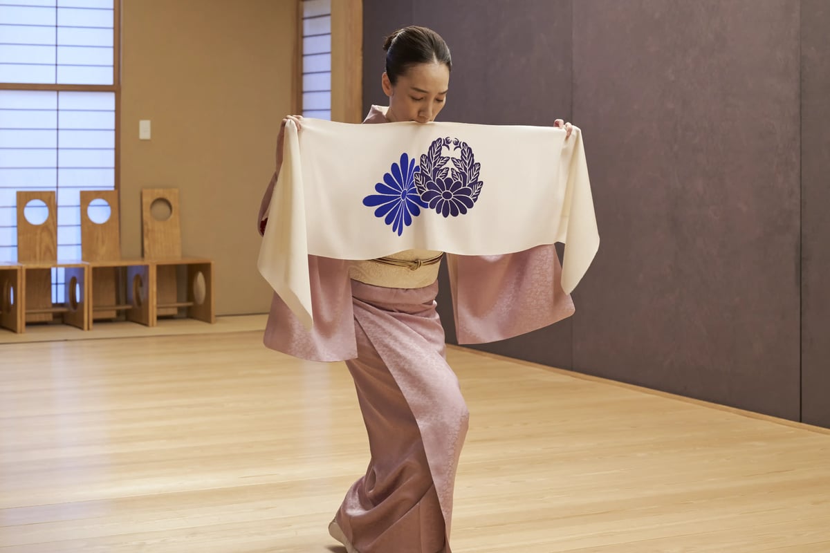 A hand towel bearing chrysanthemum crests, held open in the studio