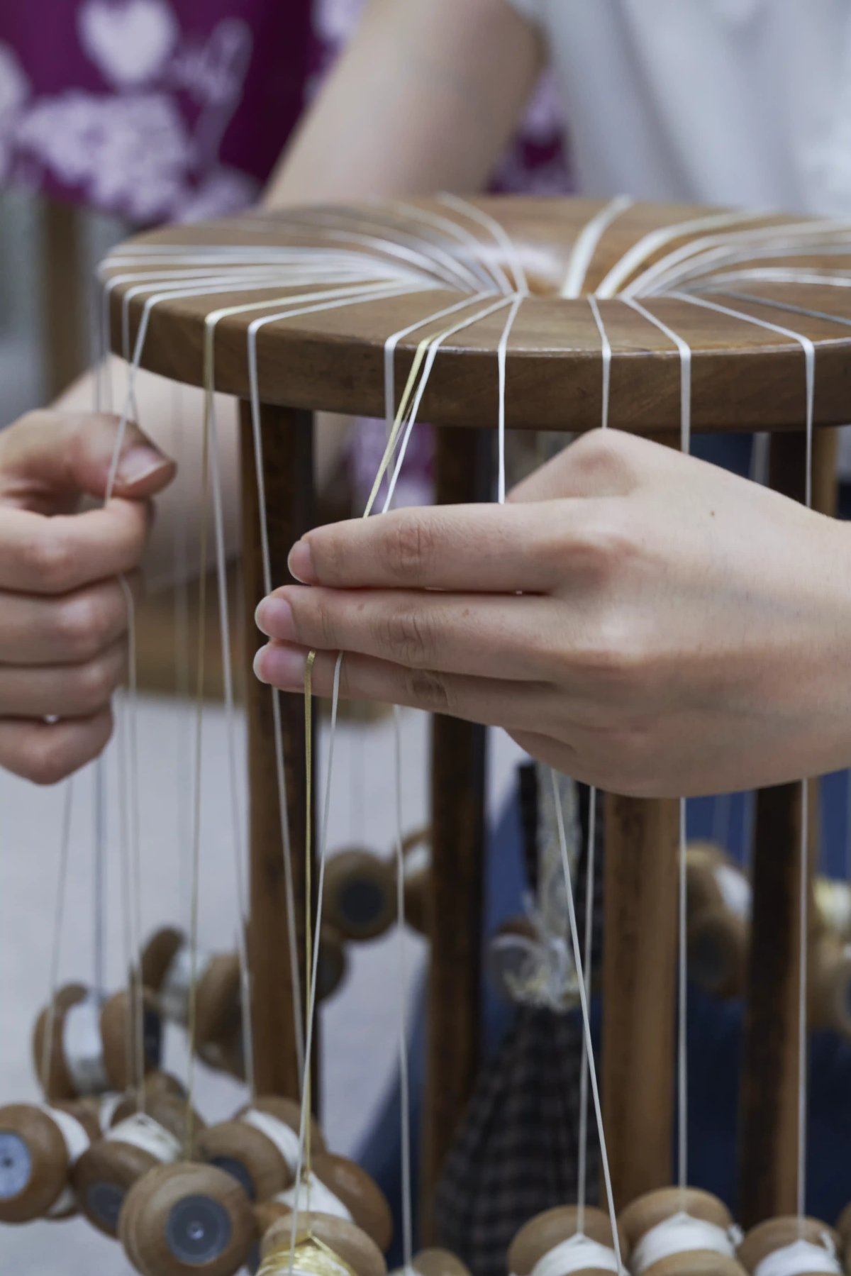 Hands moving weighted bobbins on the braiding stand