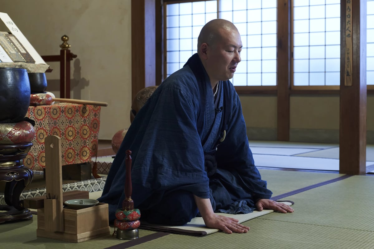 The head priest bowing low to the floor