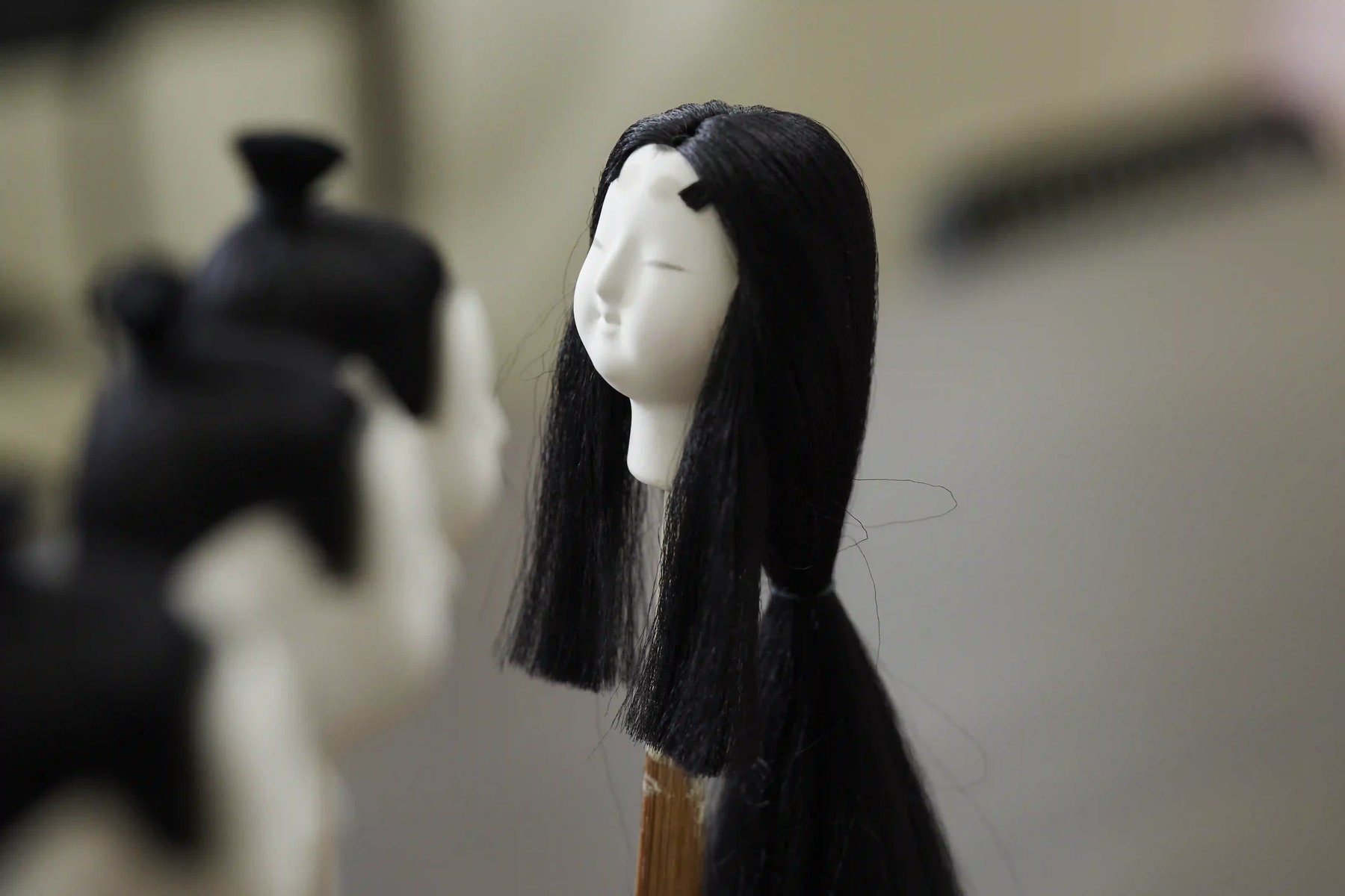 A doll's head with long black hair, waiting to be set on its body