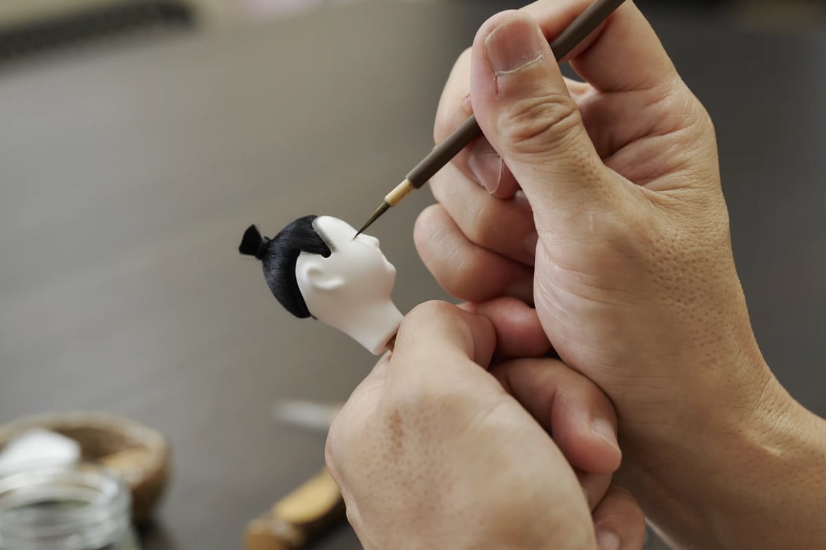 Painting a doll's face with a fine brush