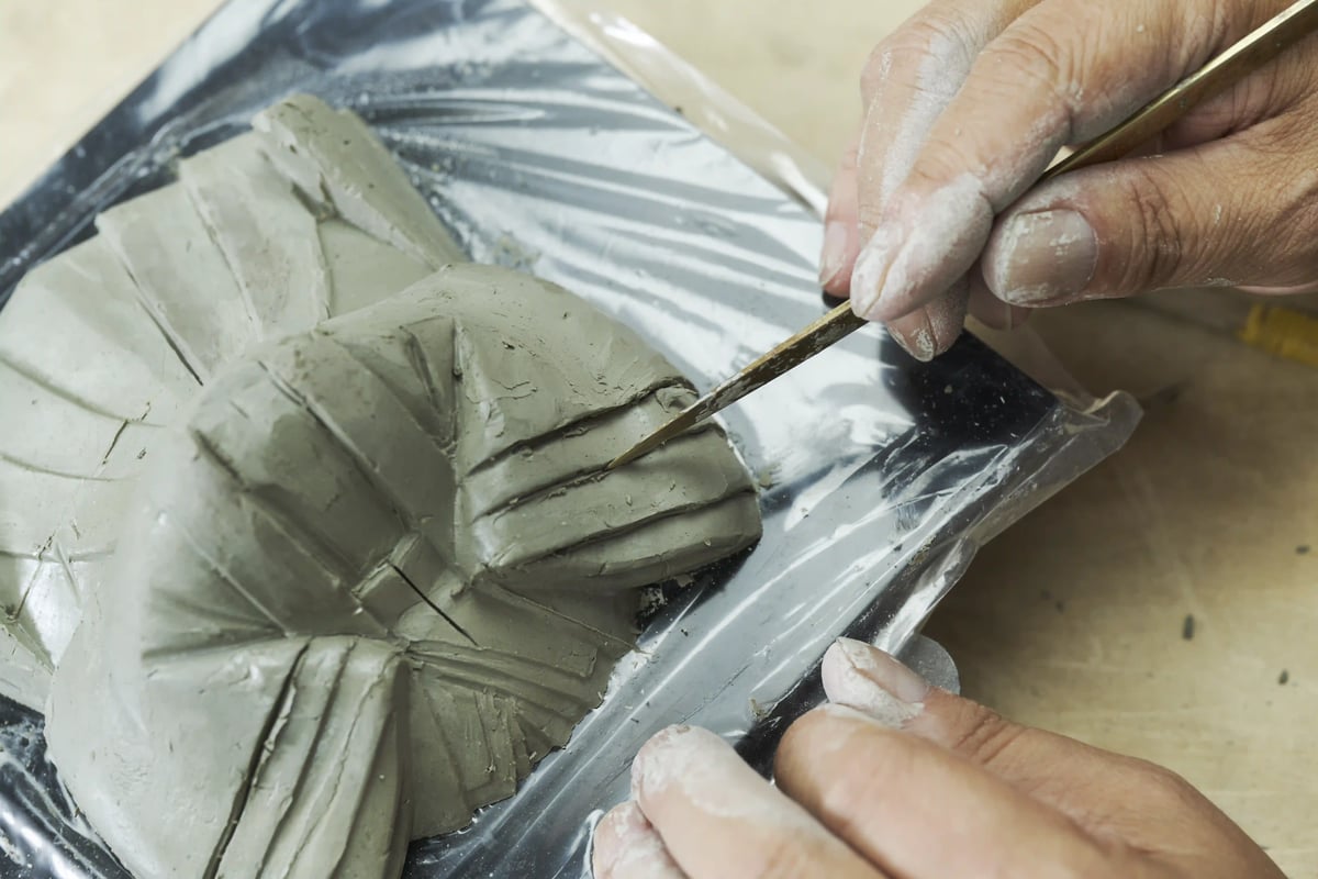 A tool working the surface of a doll body in progress