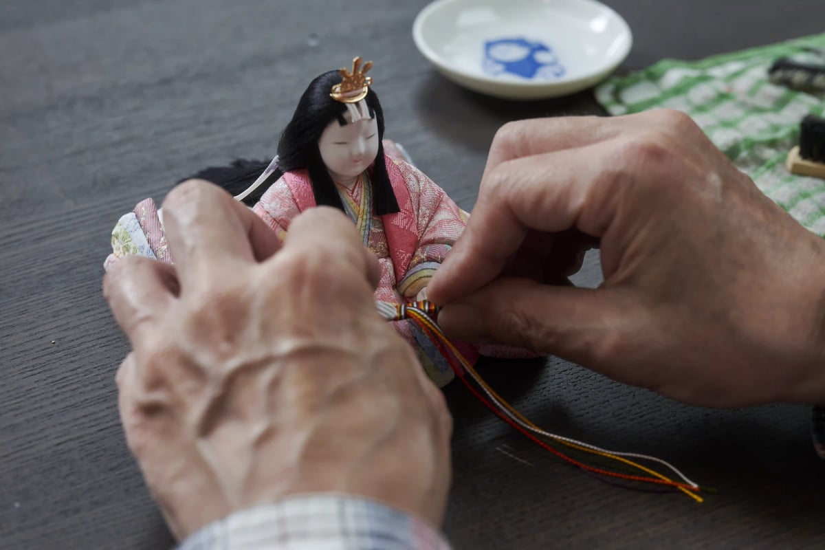Finishing touches on a hina doll's costume