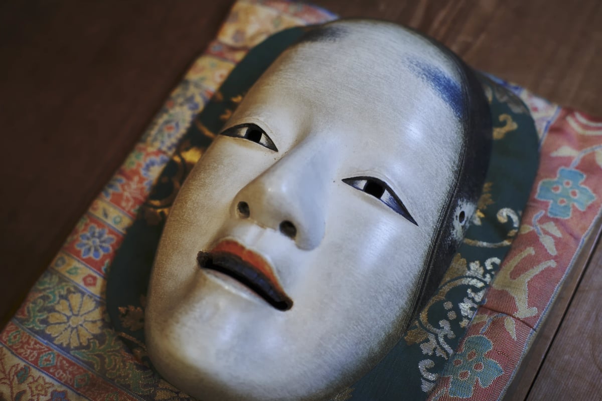 A noh mask resting on brocade