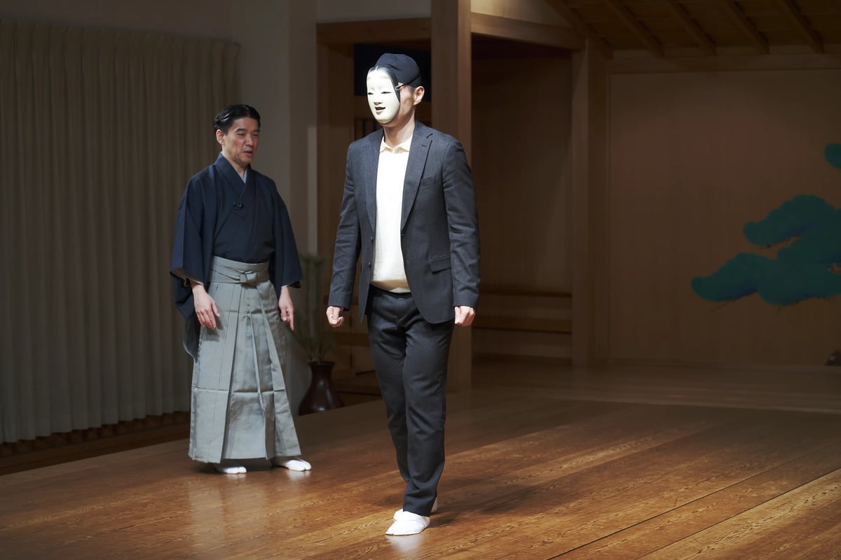 A masked visitor walking the stage with Takeda