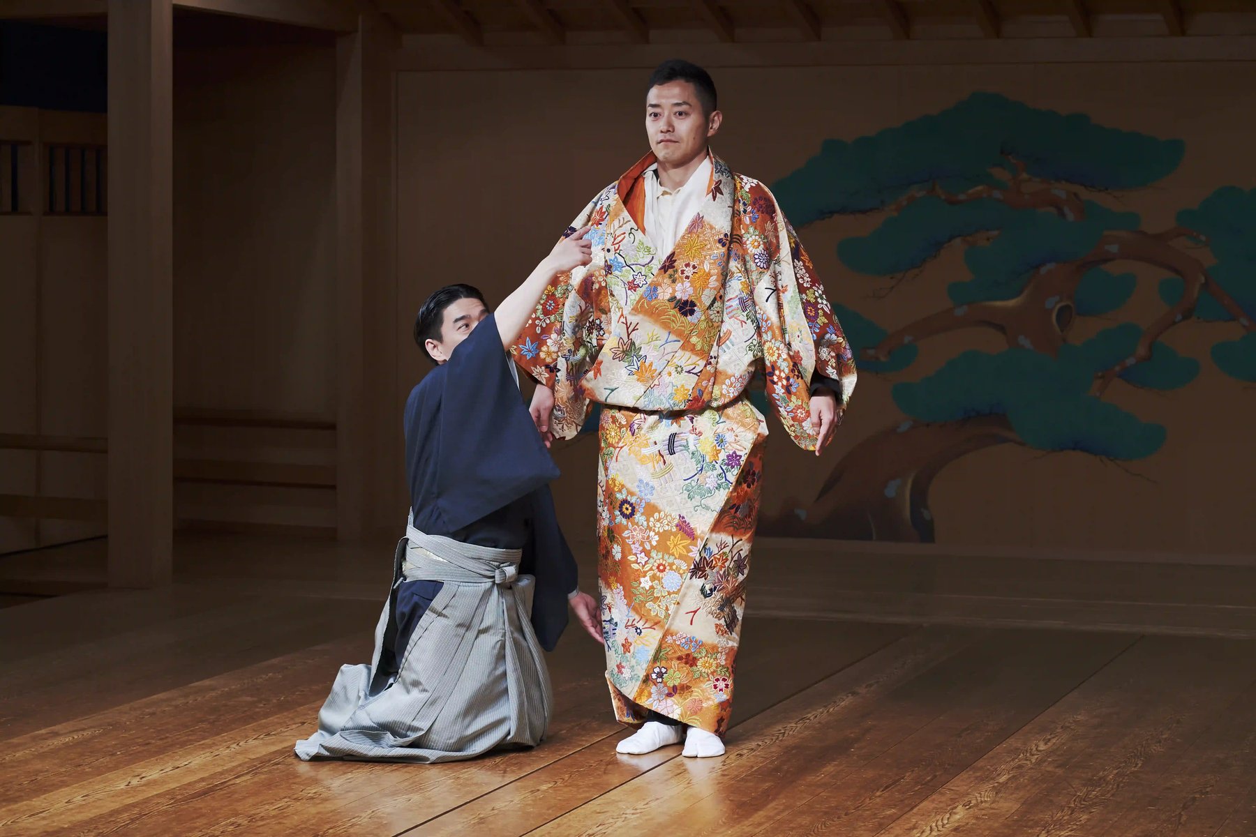 A guest in karaori robe on the noh stage beside Tomoyuki Takeda