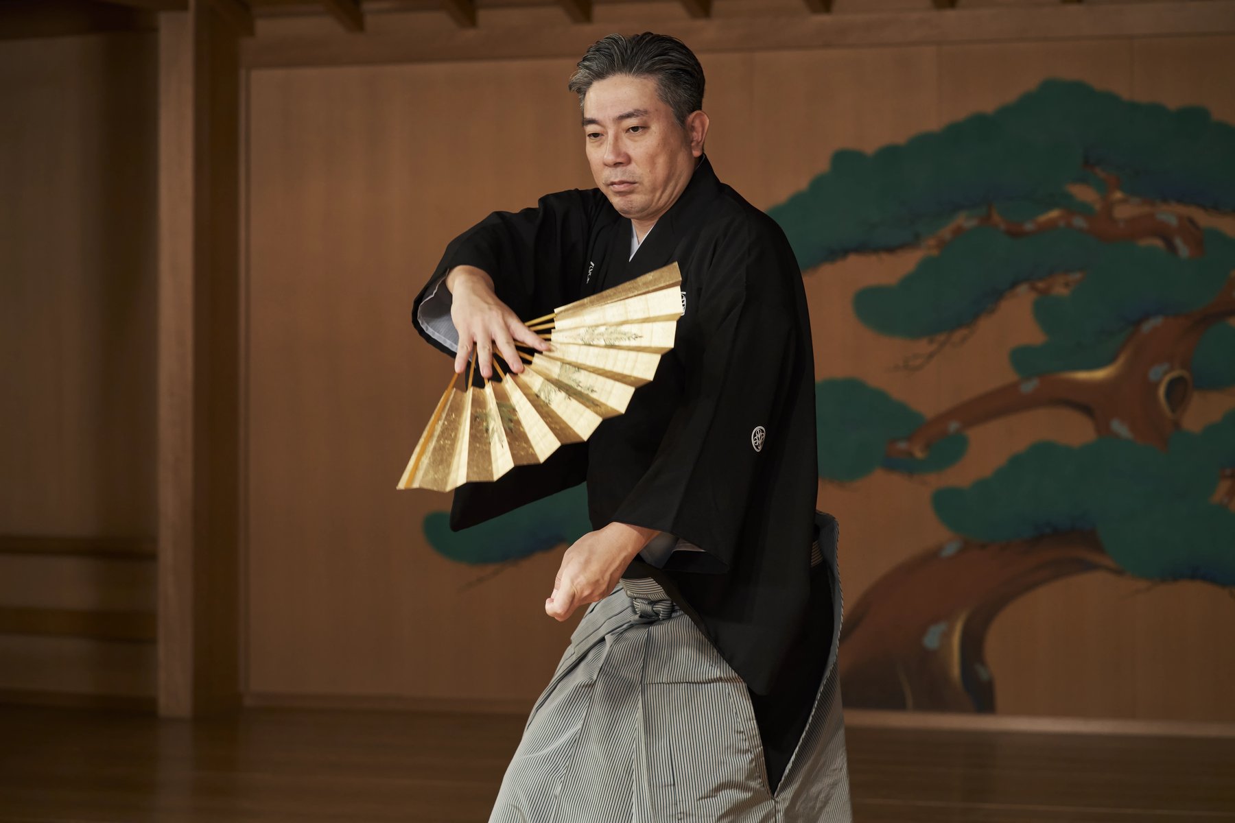 Ohkura Motonari performing kyōgen with a fan on the noh stage