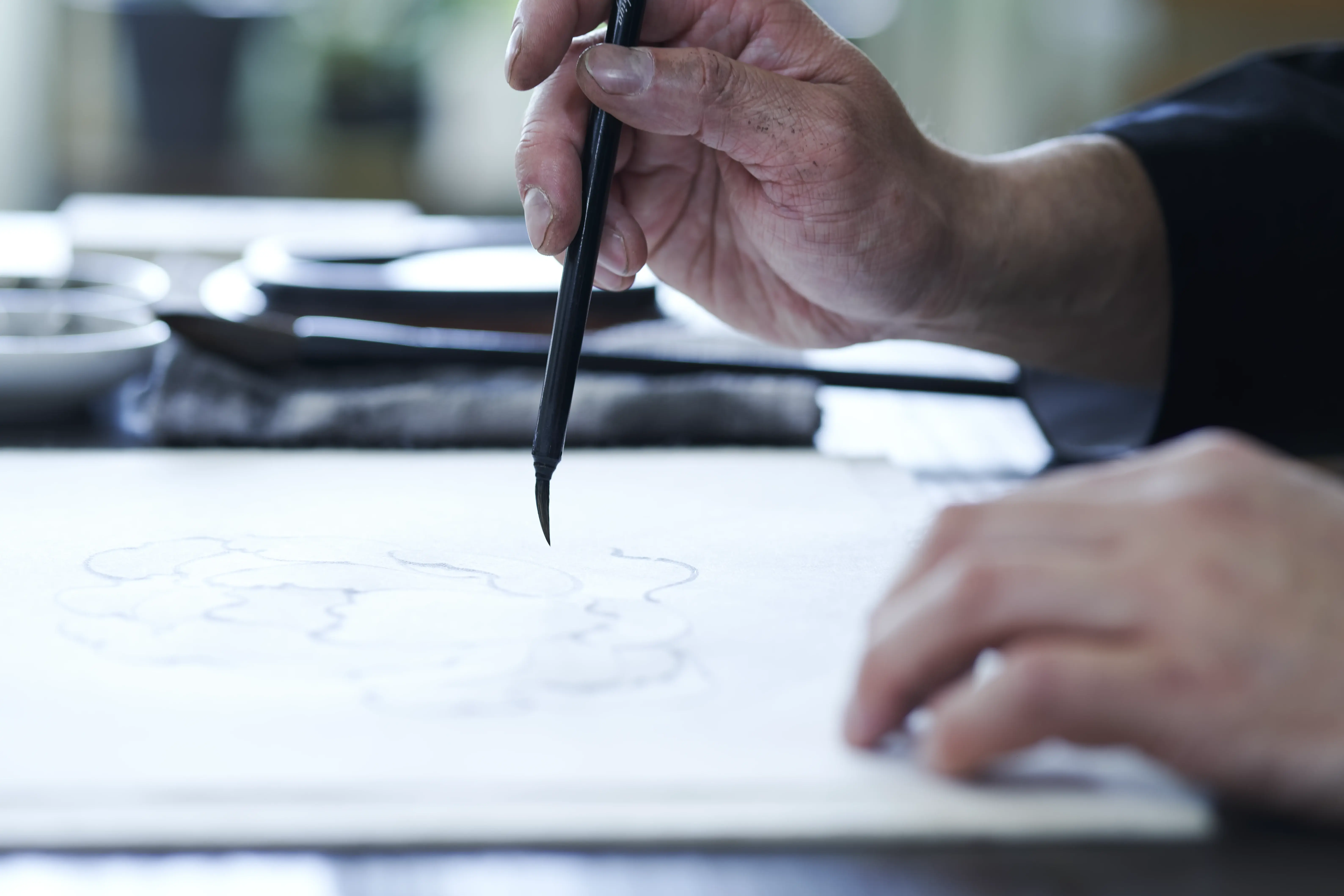 A brush loaded with sumi ink meeting paper