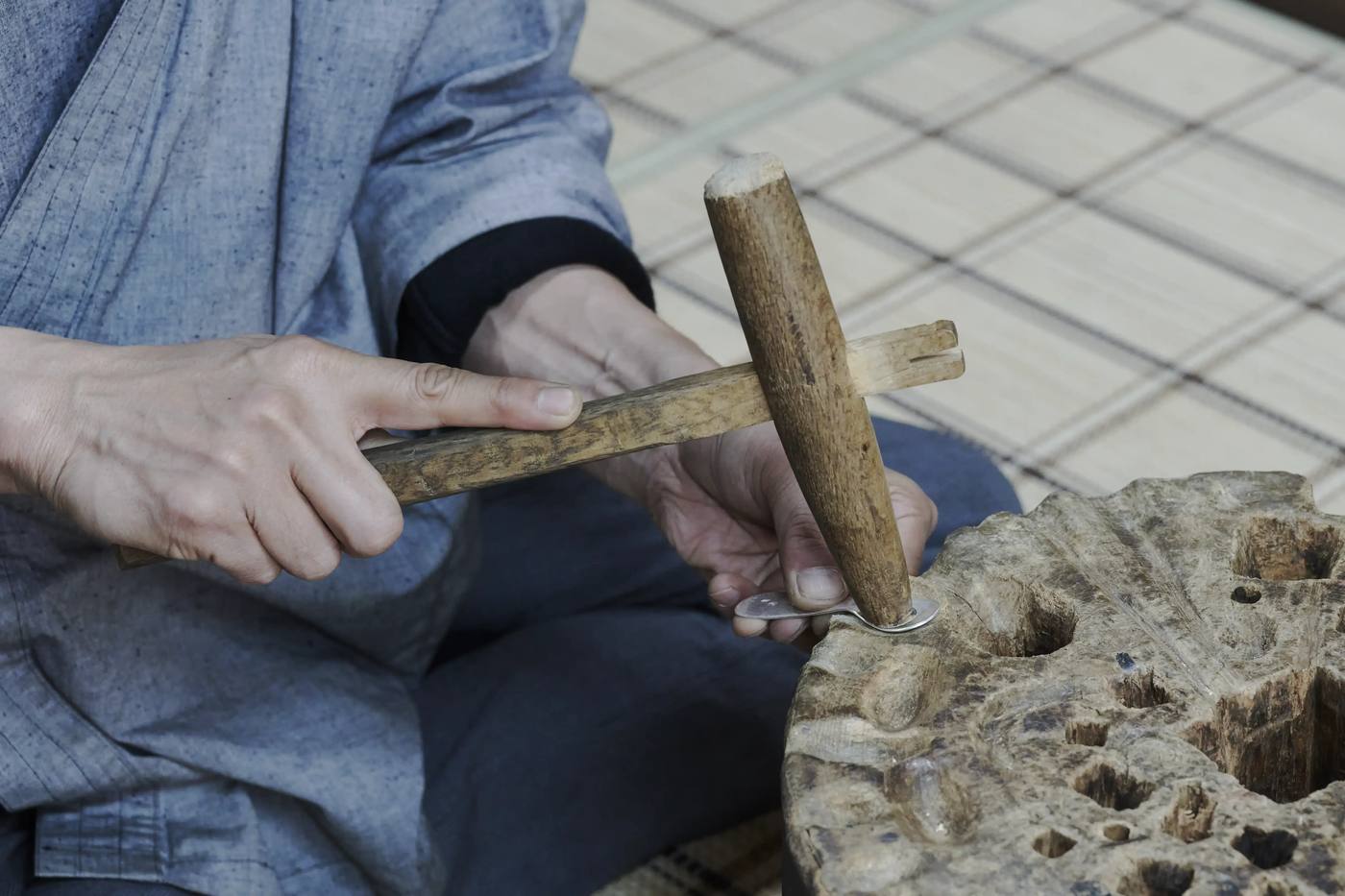A wooden mallet driving a chisel into silver